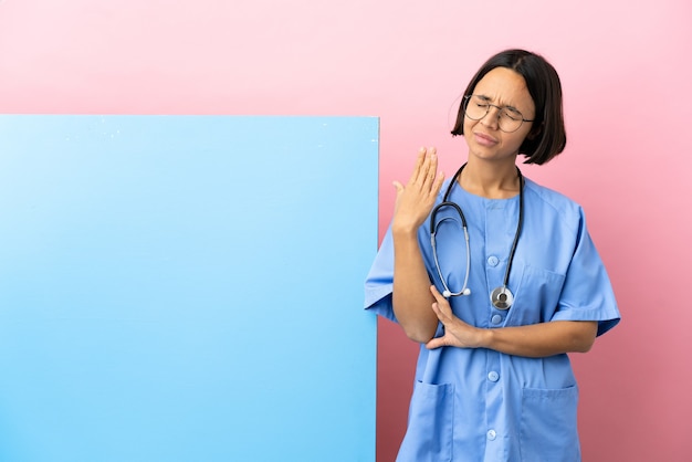 Jeune femme chirurgien métisse avec une grande bannière sur fond isolé avec une expression fatiguée et malade