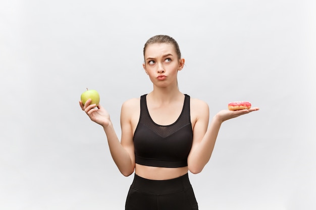 Jeune femme choisissant entre dessert et pomme régime alimentaire concept.