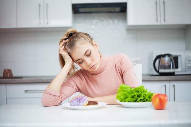 Jeune femme choisissant entre les fruits et les bonbons