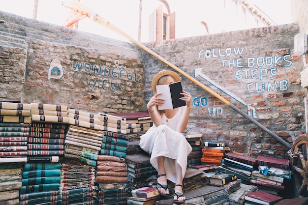 Jeune femme choisissant livre dans l'ancienne librairie d'occasion Libreria Acqua Alta à Venise Italie