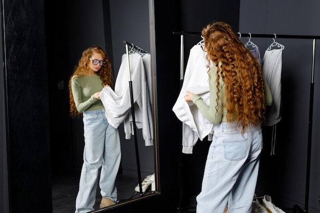 Une jeune femme choisissant des vêtements dans la salle d'essai Concept de magasinage