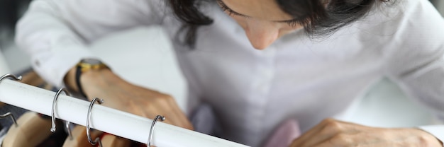 Jeune femme choisit une chemise sur des cintres dans une armoire à la maison gros plan. Équipement de magasin pour le concept de magasins.