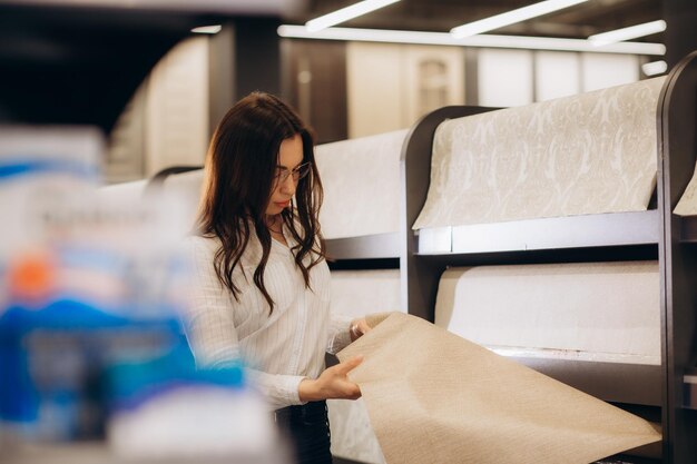 Une jeune femme choisit du papier peint pour les murs d'un nouvel appartement Concept de rénovation de style de vie de la maison Photo de haute qualité