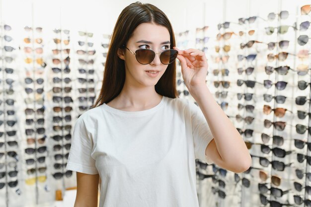 Une jeune femme choisit des lunettes de soleil dans un magasin d'optique