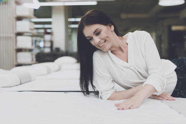 Jeune femme choisit un matelas dans un magasin.