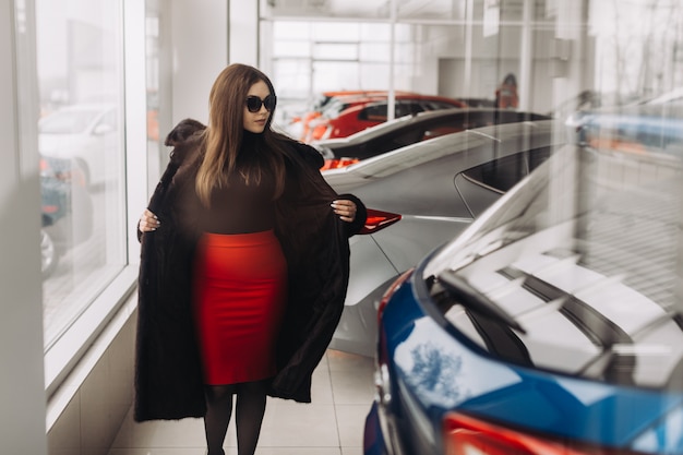 Une jeune femme choisit une nouvelle voiture dans un magasin de voitures