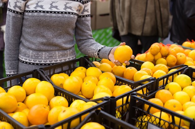 Jeune femme choisit les oranges sur le marché