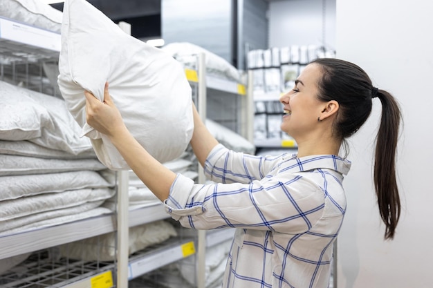 Une jeune femme choisit un oreiller dans un magasin de bricolage