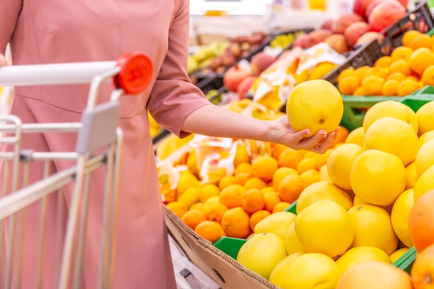 Une jeune femme choisit des pamplemousses dans un supermarché.