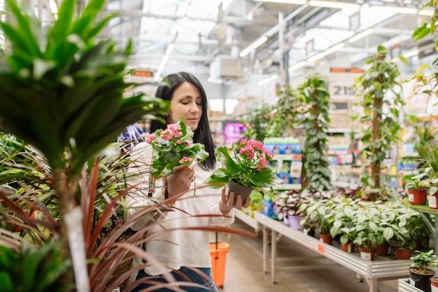 Jeune femme choisit des plantes d'intérieur dans un magasin de fleurs