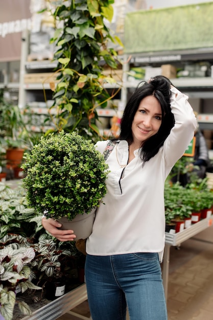 Jeune femme choisit des plantes d'intérieur dans un magasin de fleurs