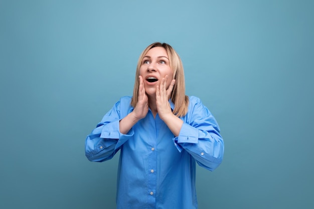 Jeune femme choquée au look décontracté saisissant sa tête sur fond bleu