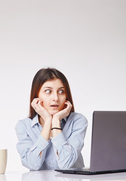 Jeune femme choquée travaillant avec l'ordinateur