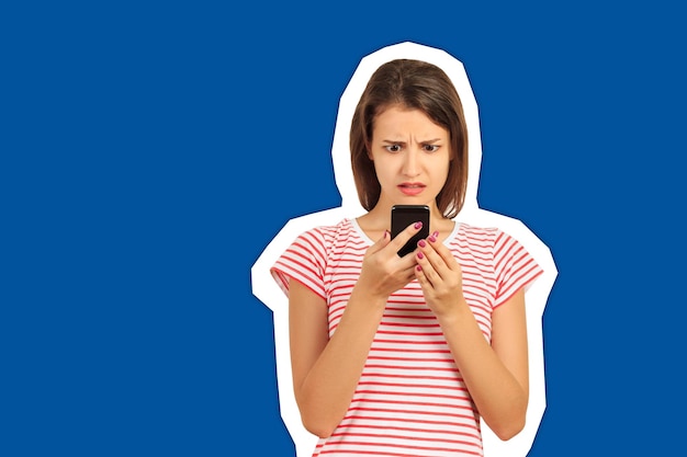 Photo une jeune femme choquée utilisant un smartphone sur un fond bleu