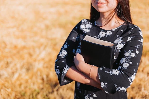 Jeune femme chrétienne méconnaissable tenant sa bible sous son bras sur le terrain. Sola scripture