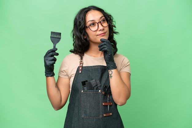 Jeune femme coiffeuse argentine sur fond isolé ayant des doutes en levant les yeux