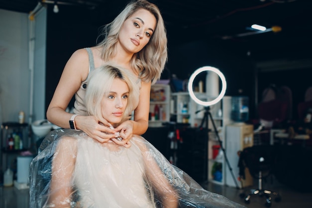 Jeune femme coiffeuse mourant les cheveux au salon de beauté Coloration professionnelle des racines des cheveux