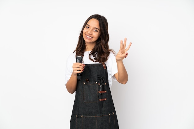 Jeune femme coiffeuse sur mur blanc heureux et en comptant trois avec les doigts