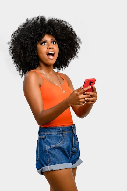 Jeune femme avec une coiffure afro tenant un téléphone portable isolé sur fond gris, concept publicitaire de personne.