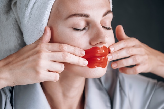 Jeune femme colle un masque cosmétique sur les lèvres.