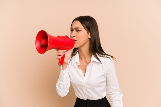 Jeune femme colombienne d'affaires criant avec un mégaphone isolé