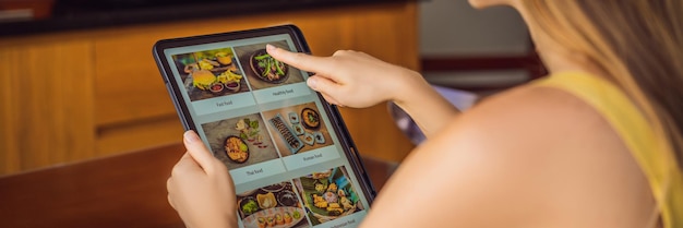 Photo une jeune femme commande de la nourriture pour le déjeuner en ligne à l'aide de tablet banner long format