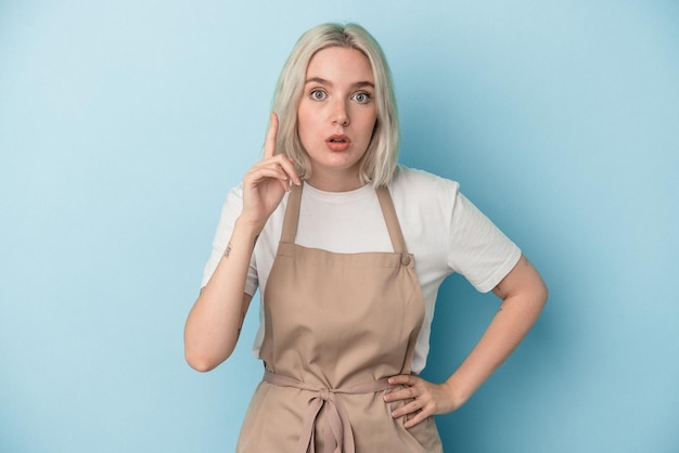 Jeune femme de commis de magasin caucasien isolée sur fond bleu ayant une idée, concept d'inspiration.