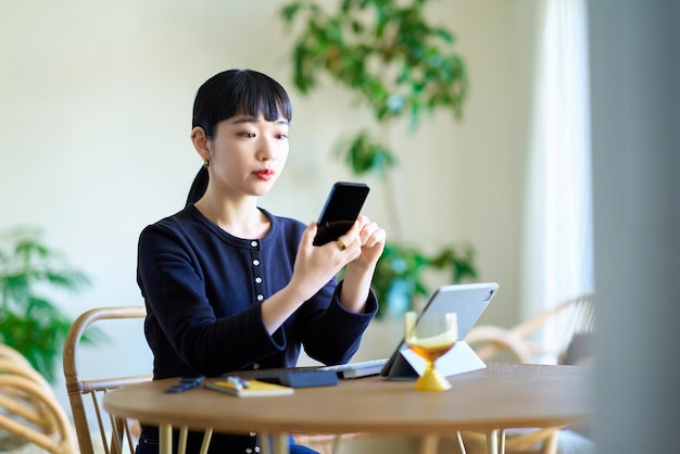 Une jeune femme compare une tablette et un smartphone