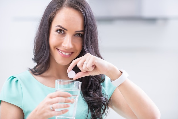 Jeune femme avec comprimé effervescent de magnésie et verre d'eau pure ou minérale