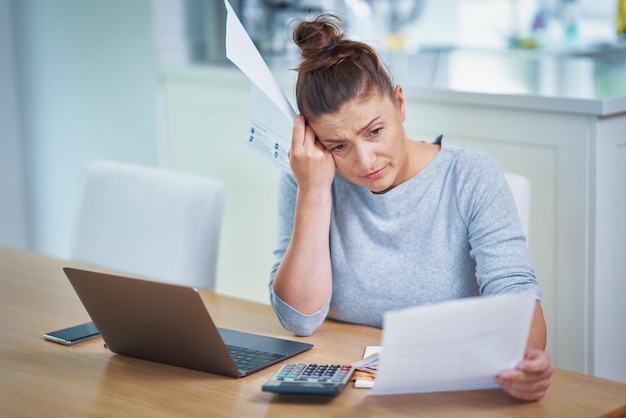 Jeune femme comptant le budget de la maison avec des factures