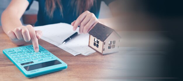 Une jeune femme compte les dépenses à la maison sur une calculatrice. achat et vente de biens