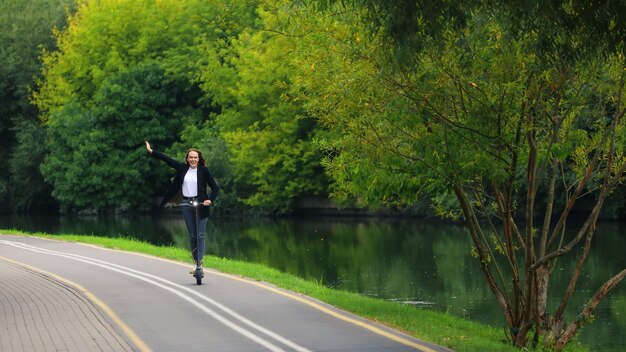 Une jeune femme conduit un scooter électrique sur une piste cyclable dans le parc