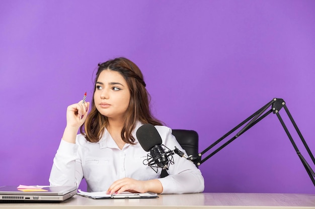 Jeune femme confiante assise derrière le bureau et pensant Photo de haute qualité