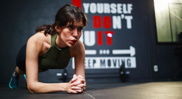 Une jeune femme confiante pose en position de planche à la salle de sport