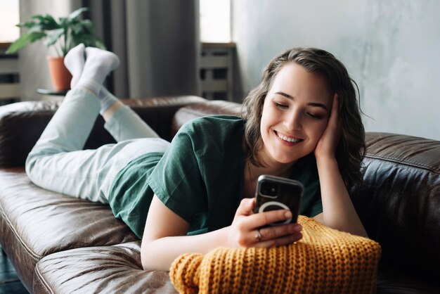 Jeune femme connectée et productive s'engageant avec un smartphone à la maison étudiante embrassant le mobile