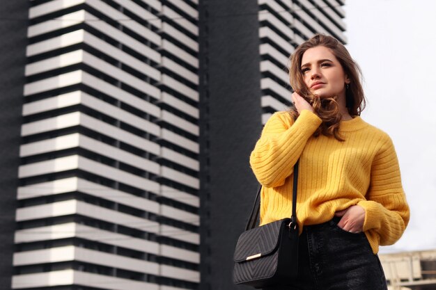 Jeune femme contre la surface des gratte-ciel dans la grande ville