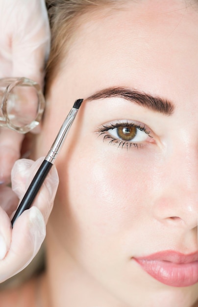 Jeune femme corrigeant la forme des sourcils avec une brosse, gros plan