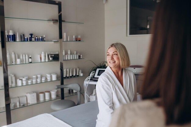 Jeune femme cosmétologue ou dermatologue dirigeant la lampe pour le traitement du visage vers une jeune femme allongée dans un salon de beauté Traitement du visage massage soins de la peau concept de cosmétologie