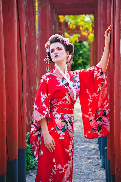 Jeune femme en costume de geisha avec maquillage fantaisie dans le jardin