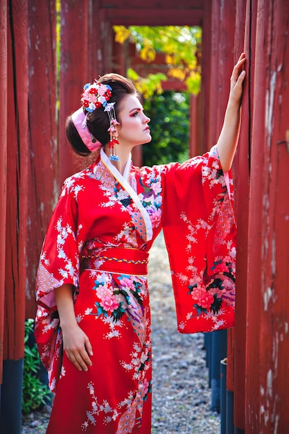 Jeune femme en costume de geisha avec maquillage fantaisie dans le jardin