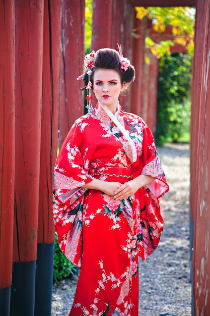 Jeune femme en costume de geisha avec maquillage fantaisie dans le jardin