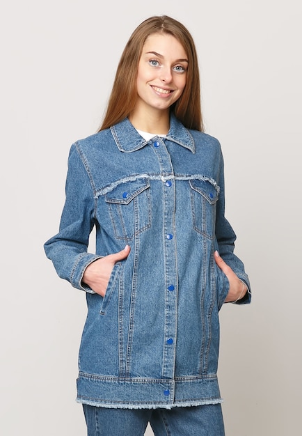 Jeune femme en costume en jean sur fond blanc. concept de photo publicitaire pour les vêtements.