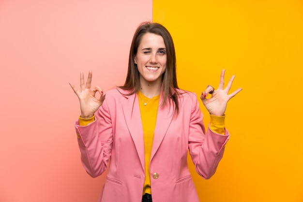 Jeune femme en costume rose montrant un signe ok avec les doigts