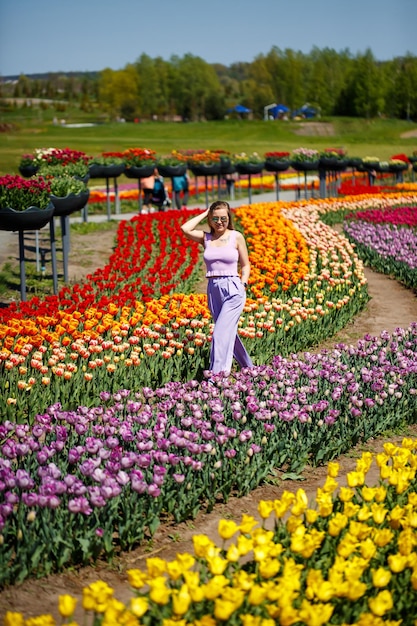 Une jeune femme en costume rose se dresse dans un champ de tulipes en fleurs. Temps de printemps