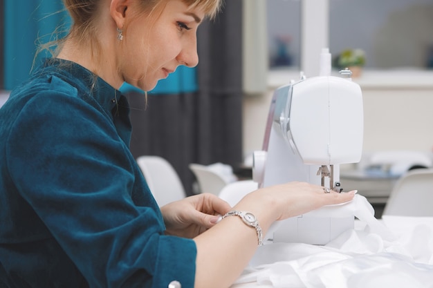 Jeune femme coud sur une machine à coudre dans un atelier.