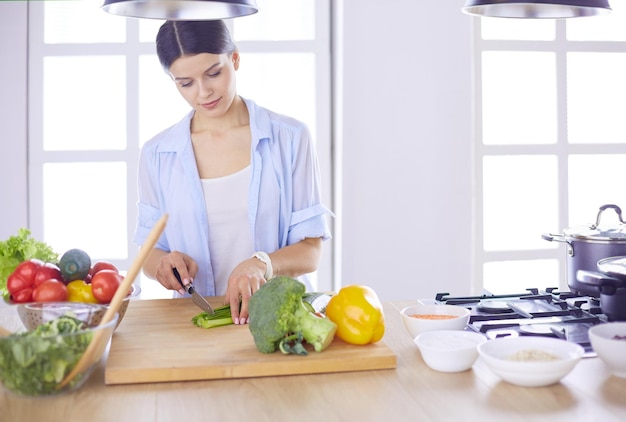 Jeune femme coupant des légumes dans la cuisine à la maison