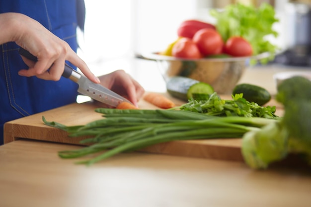 Jeune femme coupant des légumes dans la cuisine à la maison