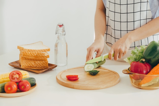 Jeune femme coupant des légumes dans la cuisine