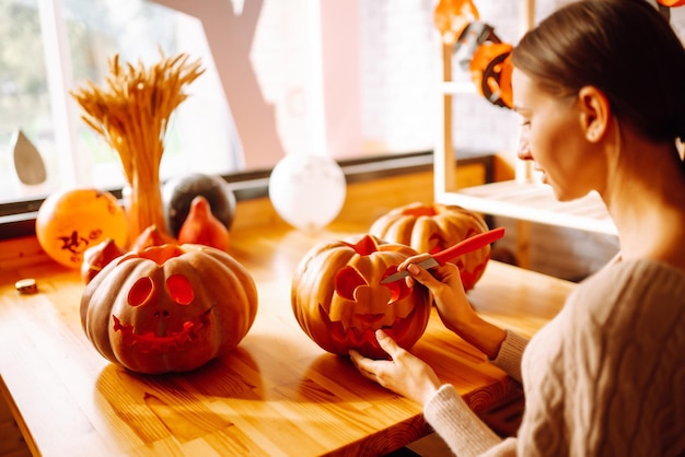 Jeune femme coupant avec le visage de personnage de couteau sur la préparation de l'objet citrouille aux vacances d'halloween