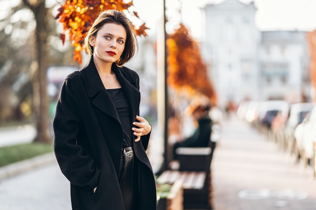 Jeune femme avec coupe courte et lèvres rouges se promenant dans les rues de la ville